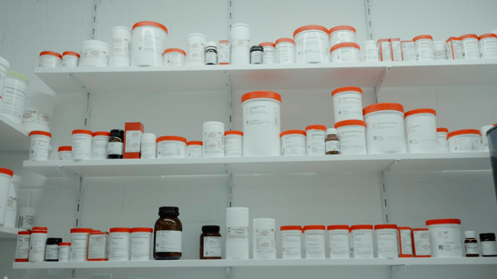 A shelf with lots of white and orange medication bottles.&nbsp;