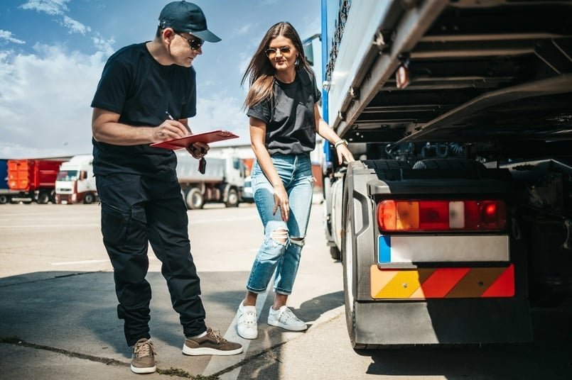 Inspector with a clipboard documenting findings while conducting a trailer safety inspection.
