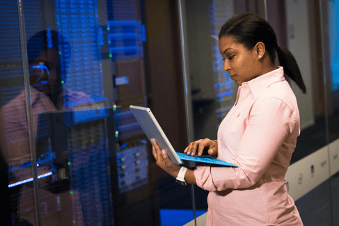 An IT professional working on a laptop in a modern server room.