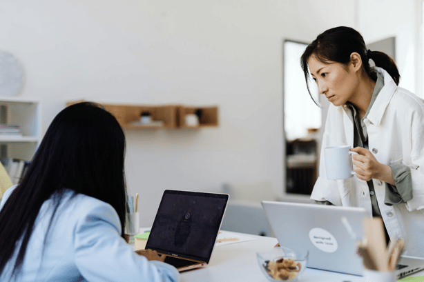 Two healthcare providers collaborating using laptops in a clinical setting