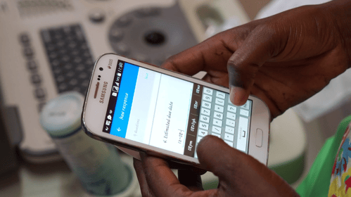 Close-up of a person holding a Samsung smartphone and entering data into a digital form on a mobile data collection app, illustrating field data entry using offline and free mobile apps.