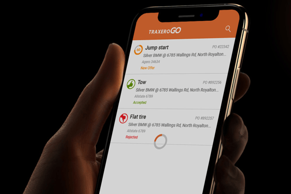 Hand holding a smartphone displaying the TRAXERO Go app