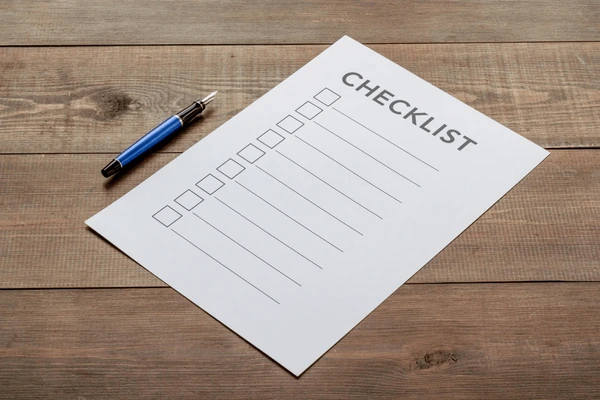 A paper checklist with a pen on a wooden surface